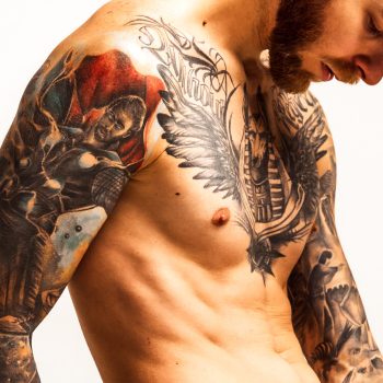 Stylish handsome young man posing shirtless. Textured muscular body shape. Tattoo body art. Concept of fashion, style, body aesthetics, beauty, men's health. Banner with copy space for ad